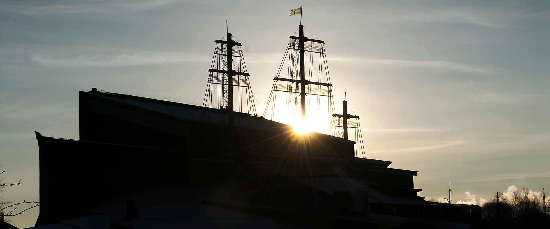 Byggnaden Vasamuseet i motljus. Masterna sticker upp över taket.